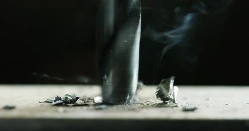 Macro shot of a drill that pierces a sheet of iron or steel. The tip of the metal drill with a cir