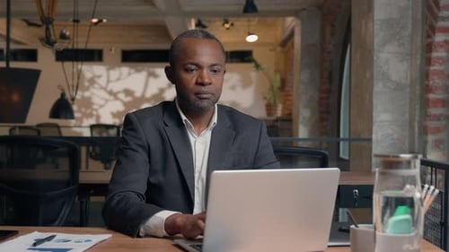 Focused Man Working on Laptop in Modern Office