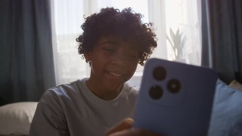 Teenager Smiles Using Smartphone At Home