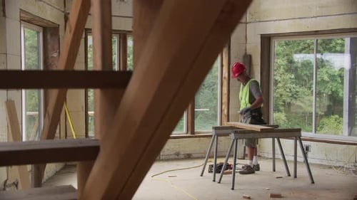 Construction worker cutting wood in unfinished home