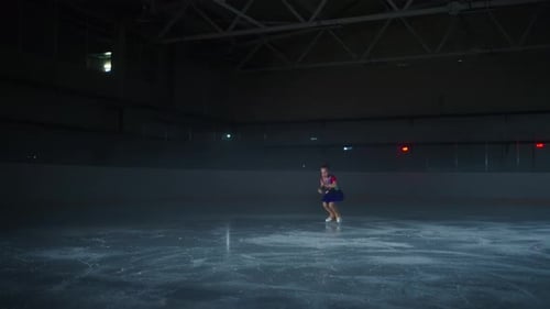 Little Figure Skater Girl Training On Ice In Dark Ice Rink In Sport Arena Performing Tricks