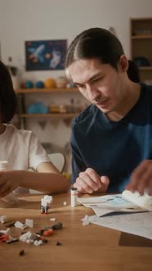 Vertical de padre e hijo ensamblando un cohete de juguete para el aprendizaje STEM