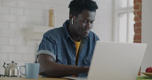 Man Works on Laptop in Kitchen at Home