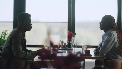 Two Young Adults Talking in an Urban Cafe