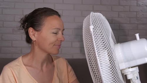 Woman Cooling Down With a Fan Indoors