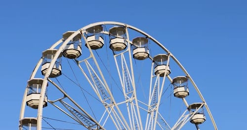 Vidéo d'une grande roue par une journée d'été ensoleillée avec un ciel bleu en arrière-plan, prise en ville