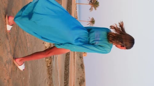 Young Girl in Swimsuit and Blue Airy Tunic Walking By Tropical Sand Beach
