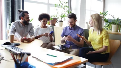 Concept d'affaires, de technologie, de personnes et de communication - Une équipe créative heureuse avec des smartphones en...
