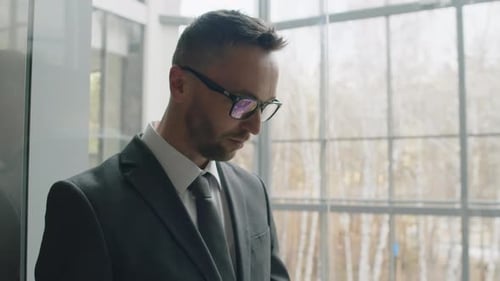 Man in Suit Using Phone in Glass Elevator