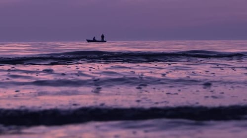 Baltic coast and purple sunset, two fishermen on boat, slow motion