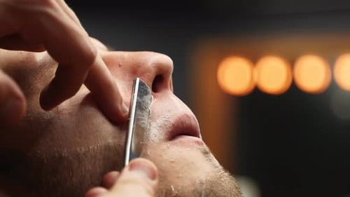 Close Up of Barber Using Straight Razor on Man