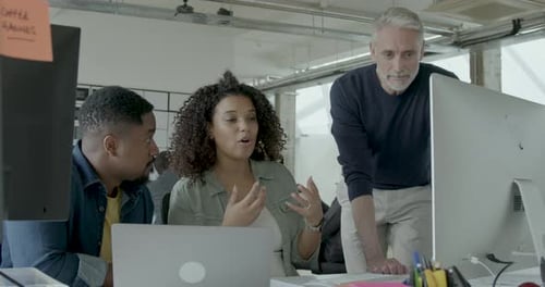Group of Coworkers Meeting round a Desktop Computer in Discussion