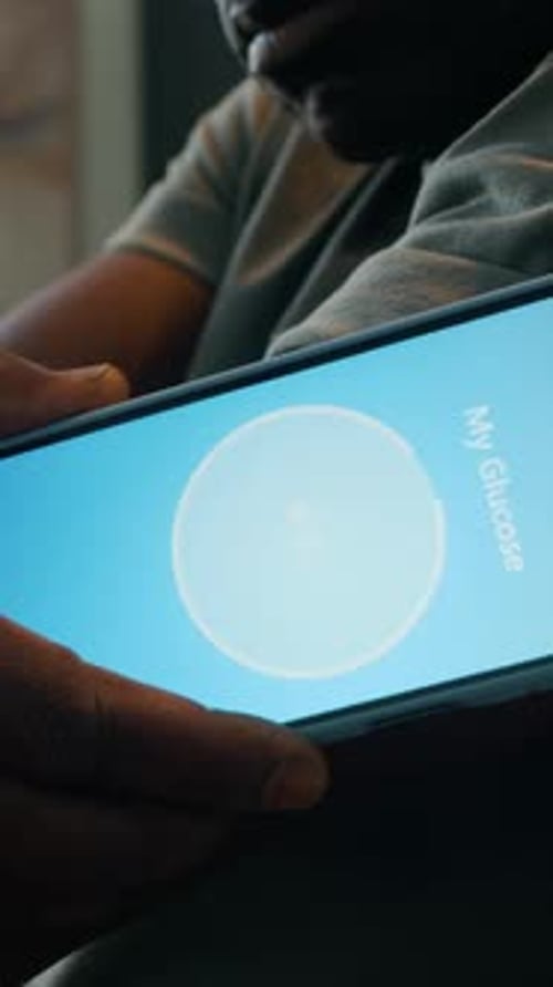 Adult Checks Glucose Level on Mobile Phone App