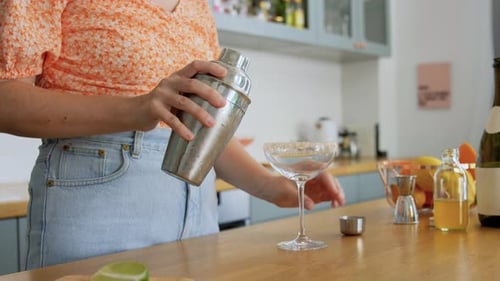 Woman making a cocktail at home in kitchen