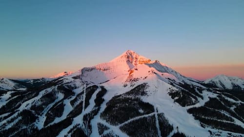 Stunning Sunset Alpenglow on Snowy Mountain Peak and Ski Trails
