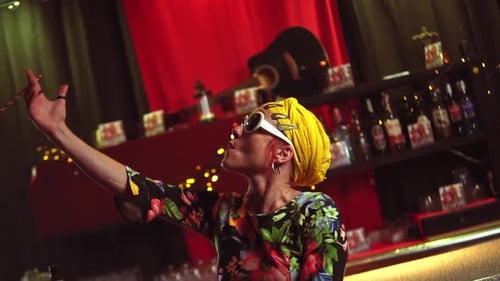 Slow motion shot of a female faking to smoke with a paper straw in a gay bar