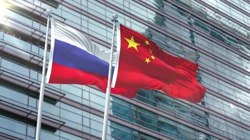 Russia and China Flags Waving in Wind Against Modern Building