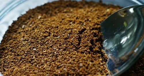 an expert bartender picks with a spoon coffee powder with the right size to make coffee of high qu