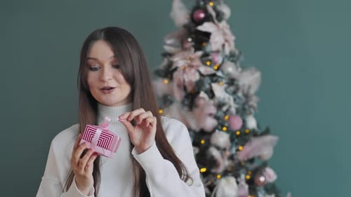 Une femme contre un sapin de Noël a reçu un cadeau