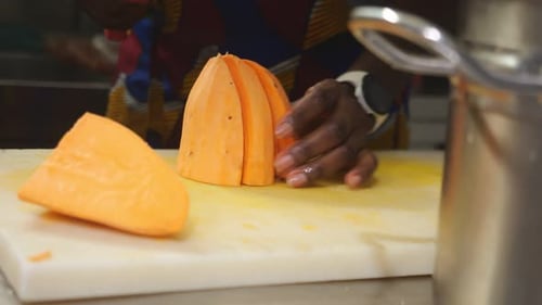 Woman chef cutting yam into concasse cubes for traditional recipe in slow motion