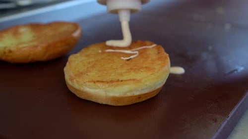 White Sauce Drizzled onto a Golden Burger Bun