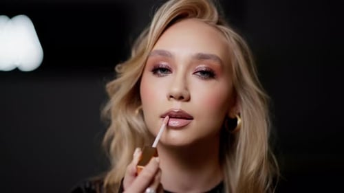 Model Applying Lip Gloss Closeup of a Model Applying Lip Gloss with a Blurred Studio Background