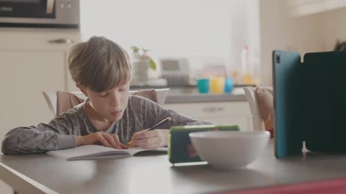 Boy Studying with Tablet at Kitchen Table