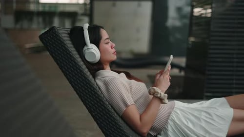 Young Woman Relaxing with Headphones and Mobile Device