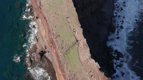 People hiking on thin mountain range cinematic with ocean on each side during sunny day. Dry brown g