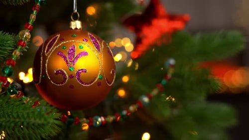 Close Up of Golden Ball on Branch Christmas Tree on Background of Fireplace
