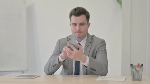 Successful Young Businessman Celebrating Win on Smartphone