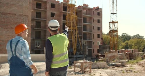 Caucasian Workers in Uniform Talking Near Building Construction