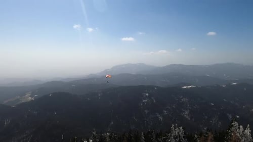 A paraglider flying in slovenian mountains in sunny winter conditions