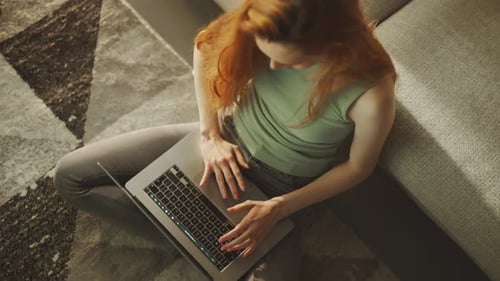 Woman using laptop sitting on floor