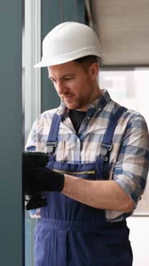 Construction Worker Using Cordless Drill on Metal Frame