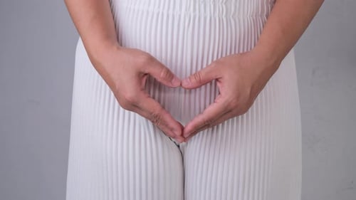 Woman holding heart shape hands on her crotch isolated on white background.