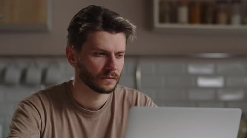 Focused Young Adult Using Laptop at Home