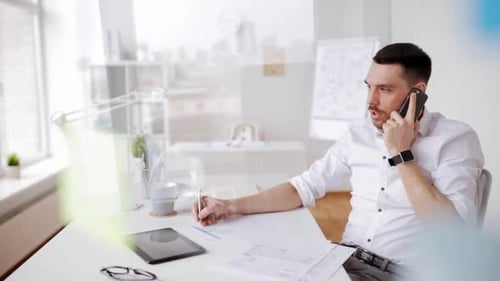 Young hispanic businessman calls on smartphone while reviewing paperwork at office