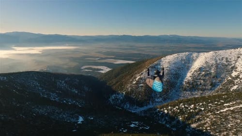 Freiheit beim Gleitschirmfliegen hoch über den verschneiten Berg