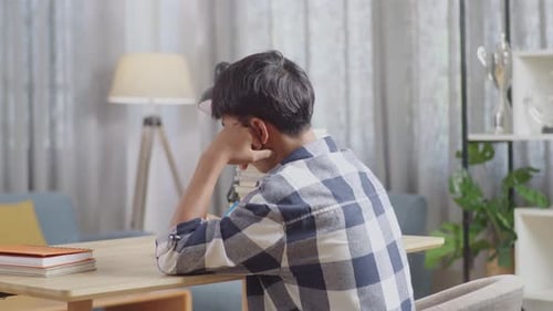 Back View Of Bored Asian Teenager Studying At Home, Asia Teen Writing While Sitting On The Table