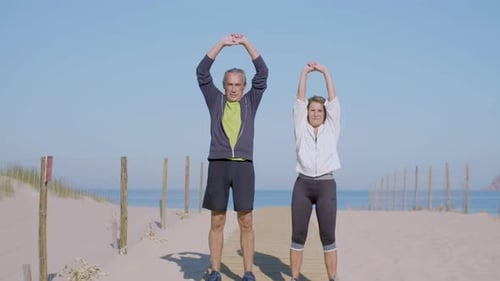 Konzentriertes älteres Paar trainiert am Sommertag am Sandstrand