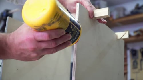 Carpenter applying PVA glue to wood to make a musical instrument in a workshop