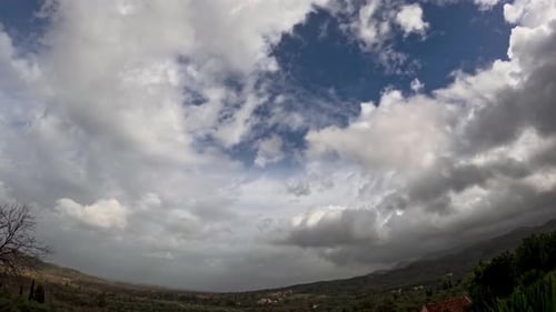 Zeitraffer dramatischer weißer Wolken, die sich schnell über der grünen ländlichen Berglandschaft bewegen, stürmisches Wetter