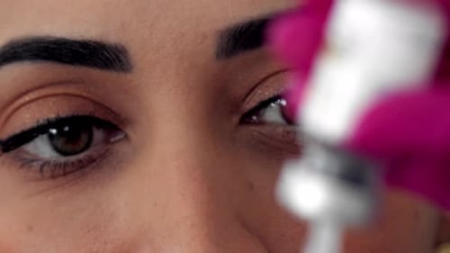 Close up of a Latina doctor's face as she fills a syringe from a vial - close up rack focus