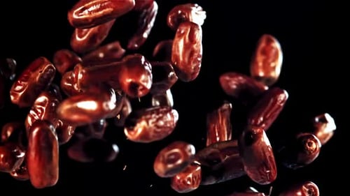 Medjool Dates Falling Against Black Background in Close Up
