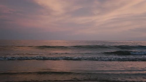 Soft Pastel Skies Reflect Over a Calm Ocean at Dusk Creating a Peaceful Beach View