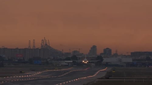 Avión aterrizando en la pista de la ciudad al atardecer