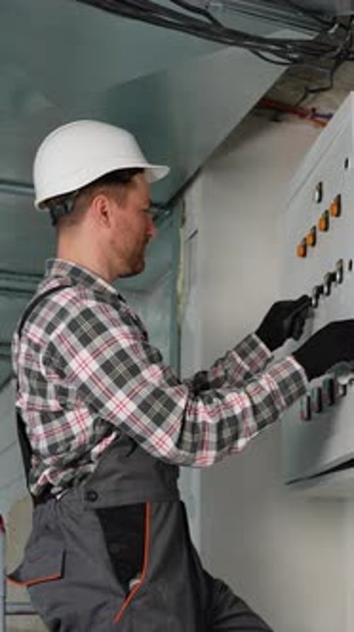 Electrician Operating Control Panel Switches in Building