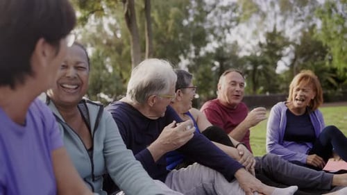 Happy senior people after yoga sport class having fun sitting outdoors in park city