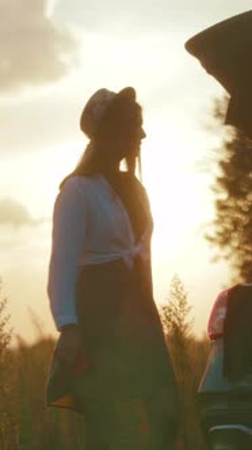 A Woman Enjoys a Sunset in a Field Relaxing with Wine in Her Car